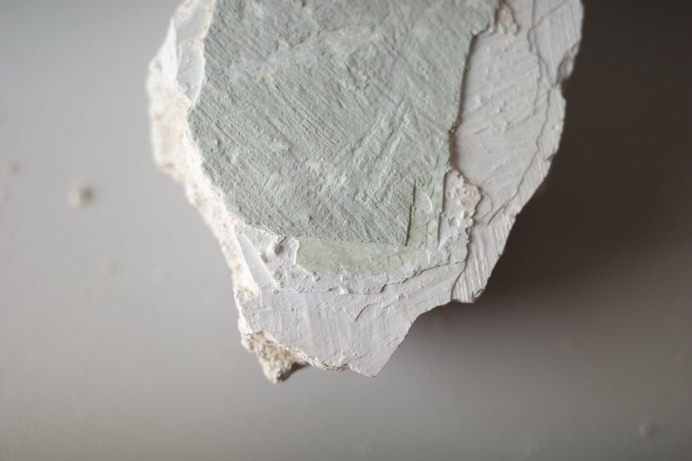 Putzfragment mit freigelegten Farbschichten in Grün und Weiß