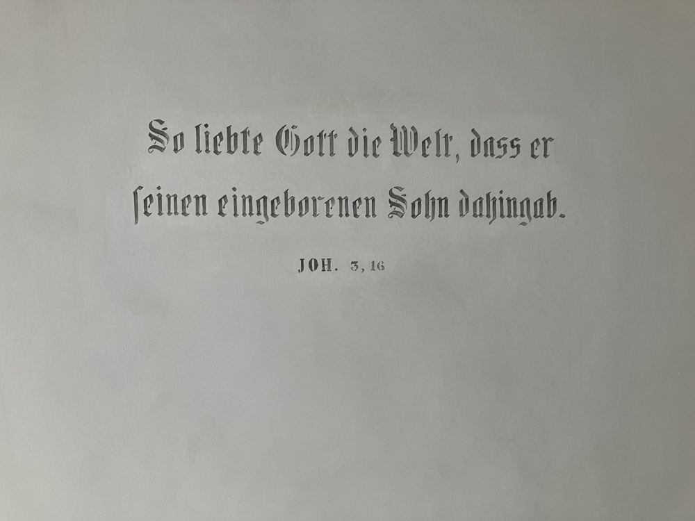 Inschrift in Fraktur: So liebte Gott die Welt, Joh. 3,16